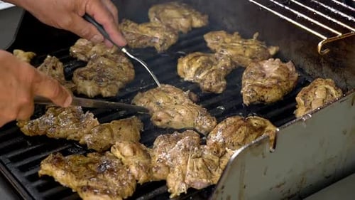 Cooking chicken on a bbq, cutting chicken pieces into smaller portions