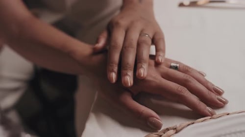 Woman places hands over another woman's hands