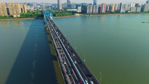 Cars Travel Over a Blue Arch Bridge While a City Skyline Looms in the Background