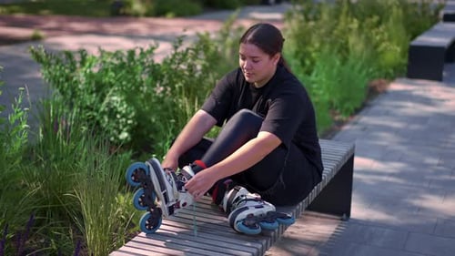 young hipster girl wearing roller skates tying laces in skate park before skating street extreme