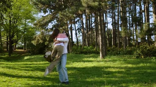 Couple Enjoys Playful Moments in Lush Green Park During Sunny Afternoon