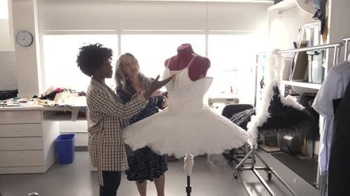 Female Costume Designers Examining White Tutu on Dressmakers Model Adult
