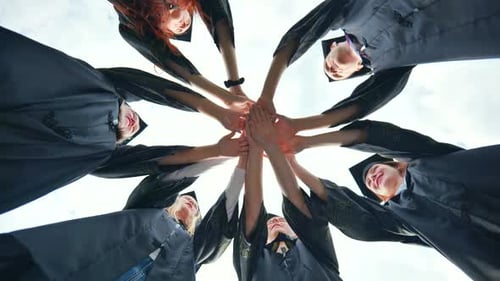Graduates in Black School Uniforms Join Hands The Concept of Team and Strong Friendship