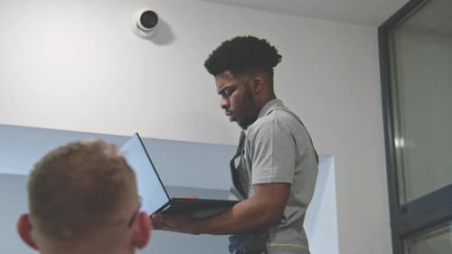 Two Multi Ethnic Installers Sets Up Security Cameras in Office Hallway