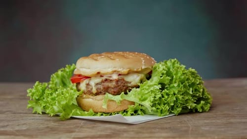 Close up of Big Burger lies on craft white paper against wooden table