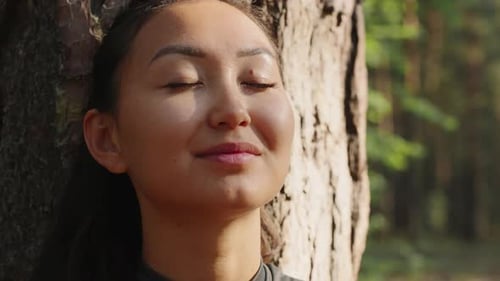 Young Asian Woman Meditating Near a Tree in the Forest