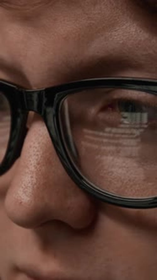 Vertical Close-up of Man Wearing Glasses with Screen Reflection of Code