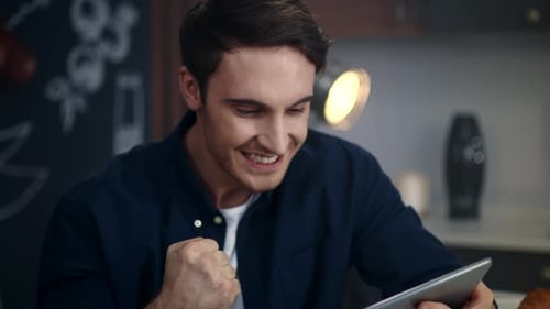 Excited Young Man Reacting to Good News on Tablet