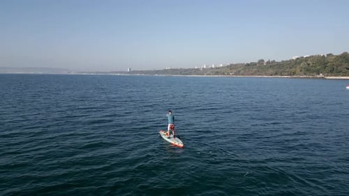 Aerial View of a Man Paddling a Standup Paddleboard or SUP Board on a Calm Sea