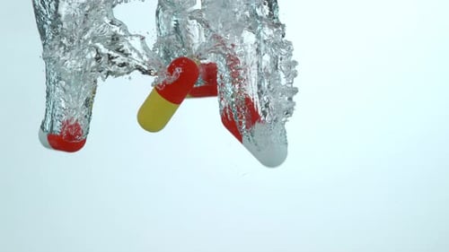 Pills Dropping into Water with Bubbles in Slow Motion