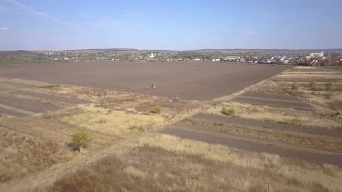 Top Down Aerial View of Green Tractor Cultivating Ground and Seeding a Dry Field Farmer Preparing