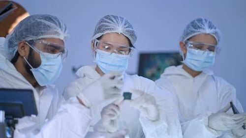 Highly focused group wearing full protective gear evaluates a newly manufactured processor