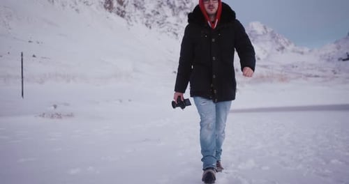 Man Walks Through Snow With Mountain Backdrop