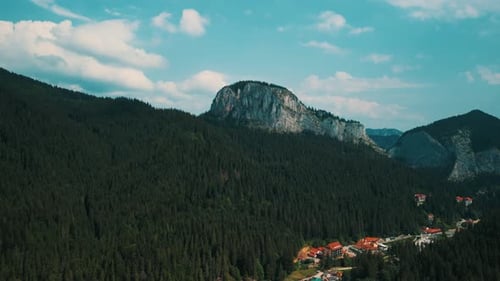 Majestic Mountain Range with Lush Forests Charming Village Below