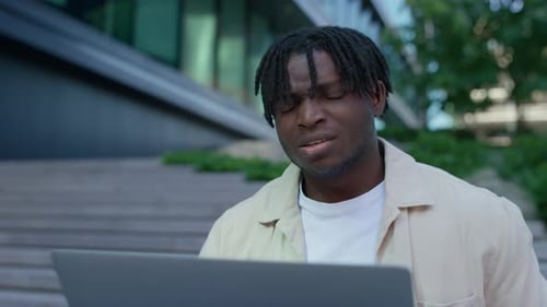 Frustrated Student Struggling with Laptop Outdoors