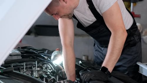A Car Mechanic Works in a Garage He Repairs a Car Engine Service Repair