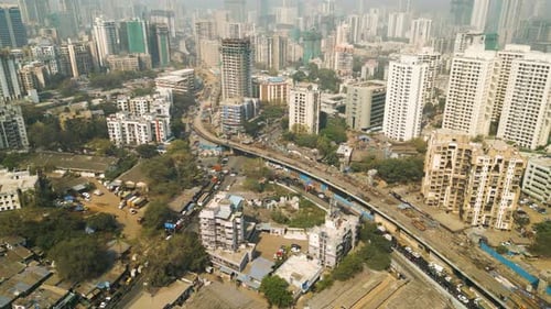 Highway winds across Mumbai India passing over construction site, aerial cityscape