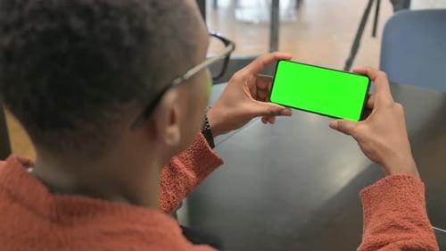 Back View of African Man Holding Phone Horizontal with Green Screen