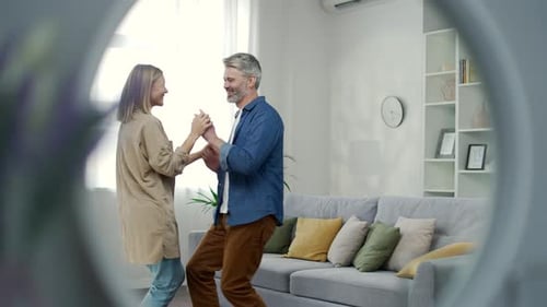View in the mirror. Family couple having fun dancing a dance holding hands in the living room