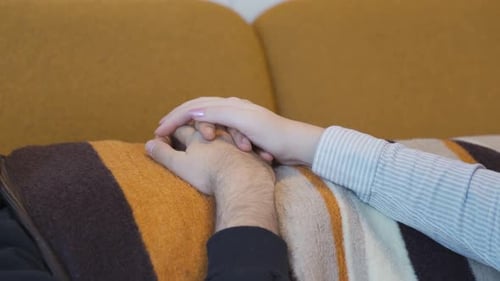 Die Frau hält die Hand ihres Mannes.