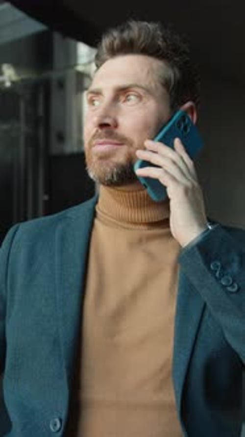 Nahaufnahme Attraktiver junger Mann in stylischer Jacke telefoniert am Telefon und schaut sich um. Fühlen Sie sich drinnen glücklich