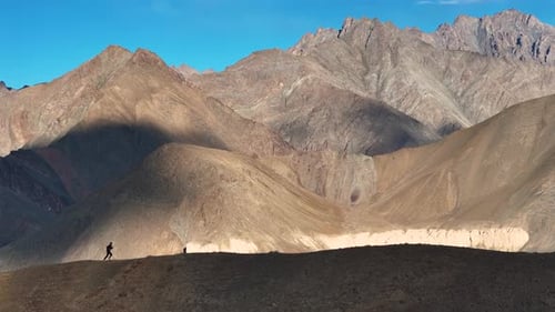 Aerial Drone shot of minimal human standing on the clif of the mountain in leh ladakh