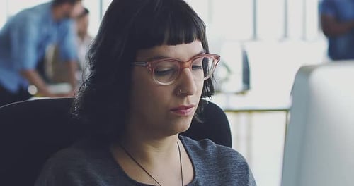 4K video footage of a young designer working at her computer in a modern office