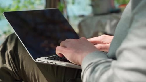 a Young Male Programmer Working at a Computer Outdoors