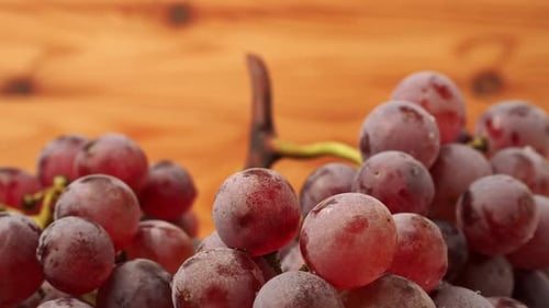 Rote Trauben rotieren auf einem hölzernen Hintergrund.