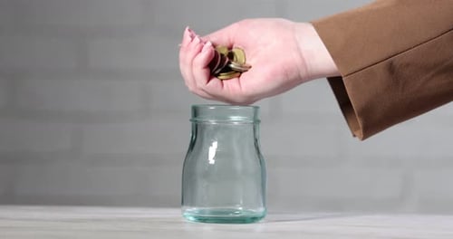 Depositing Coins into a Glass Jar for Savings