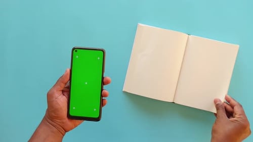 Hand holding cellphone with green screen, reading