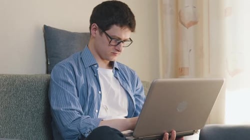 Man Works on Laptop While Relaxing on Couch