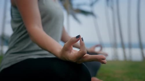 Beautiful Woman Doing Yoga Exercise and Breath Meditation Sitting on Green Grass