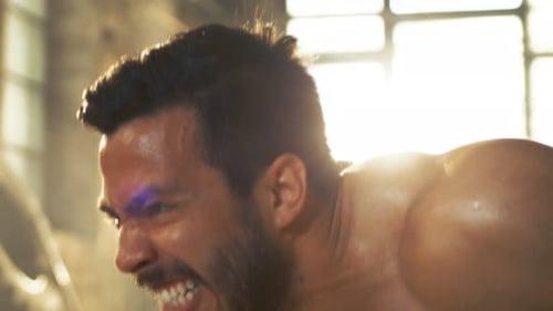 Muscular Shirtless Man Covered in Sweat Does Push-ups in a Deserted Factory Remodeled into Gym. Par