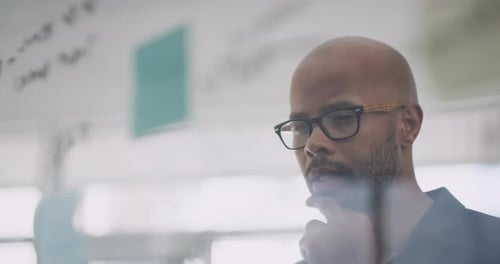 Man Planning with Notes on Glass in Office