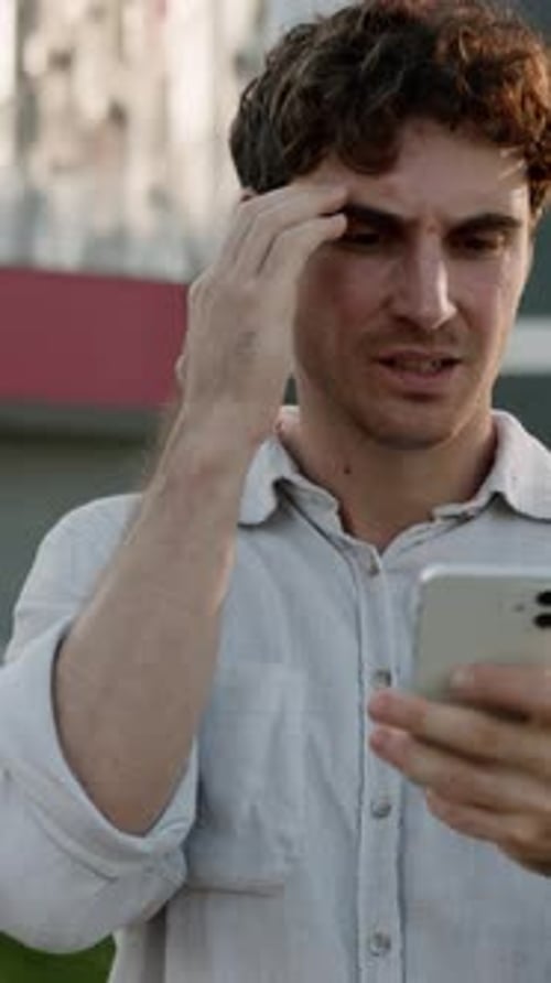 Man outside with phone, thinking, confused, and frustrated