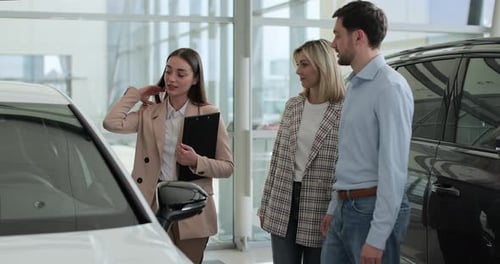 Happy Family Couple Talking to Car Dealer in Dealership Discussing Automobiles Looking at New Model