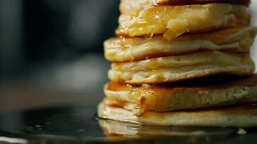 Close up honey spreads over the pancakes