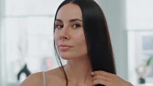 Woman brushes hair in a bright home