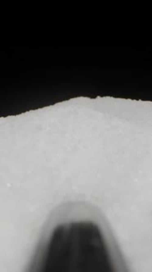 Vertical video. A spoon is removed from a pile of sugar, and it moves backward. Concept of unhealthy