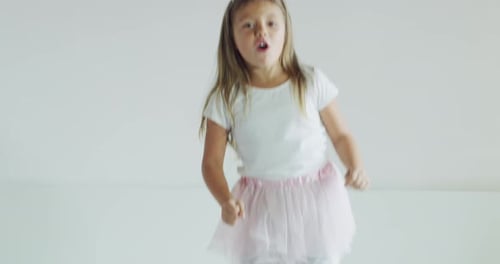 Girl in Tiara Jumps on White Bed