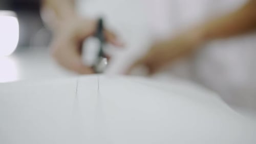 Male hands cuttting white cloth on the table with scissors.