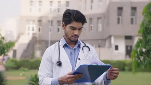 Young Doctor Taking Notes Outside Hospital