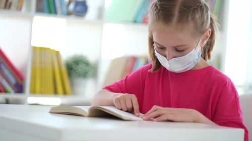 Little Girl Reading Book While at Desk