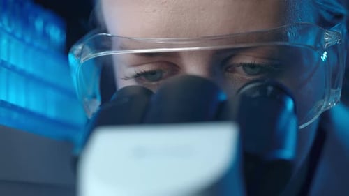 Woman Scientist Looks Through Microscope in Lab