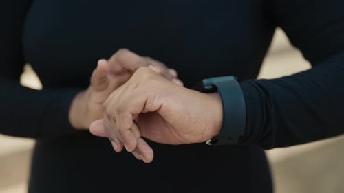 CloseUp of an Athlete's Hand Adjusting a Digital Smart Watch Before Run