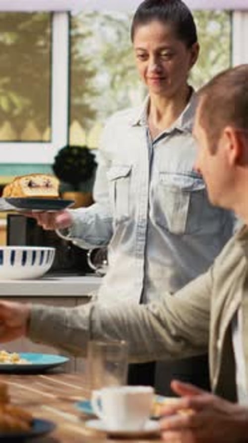 Vidéo verticale Famille avec une préadolescente servant le petit déjeuner ensemble dans une cuisine lumineuse