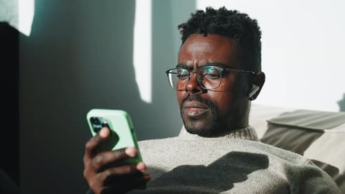 Man Using Cellphone Wearing Wireless Earbuds Indoors
