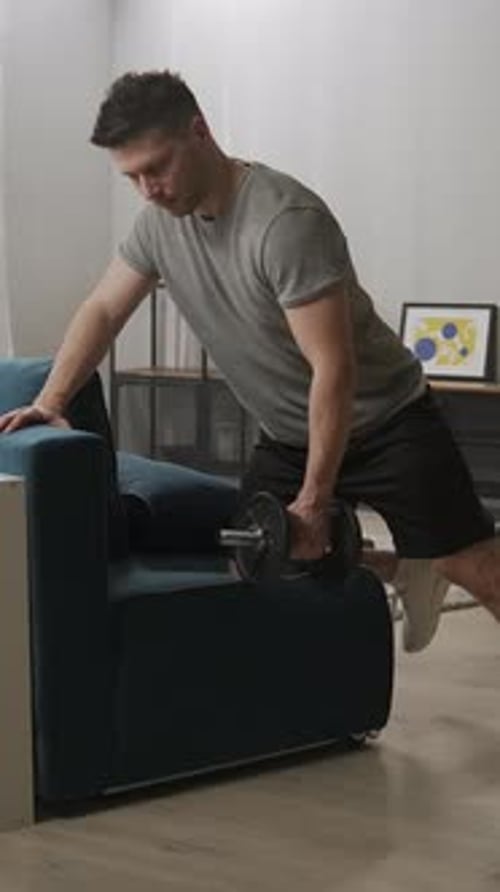 Focused Home Workout Sequence of Man Performing Dumbbell Row Exercise Using Living Room Sofa for