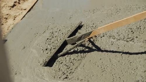 Worker Leveling Wet Concrete with Tool